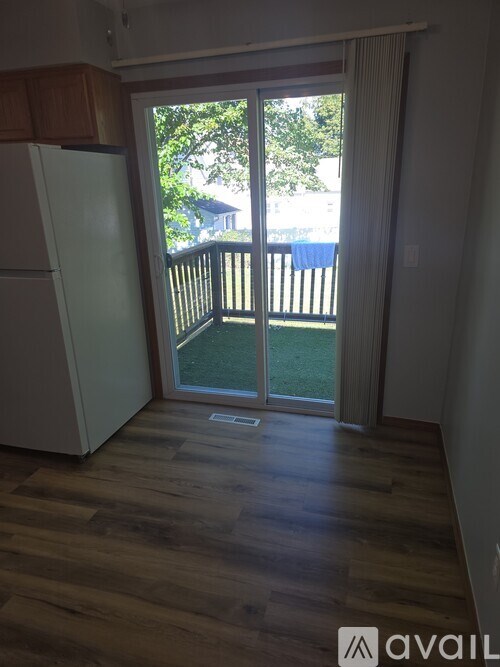 A kitchen with a white fridge and wooden floors.