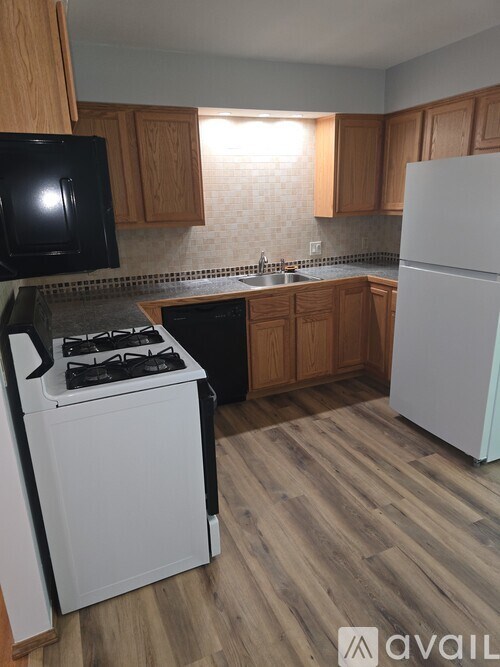 A kitchen with a white refrigerator, black microwave, and a white stove with black handles.