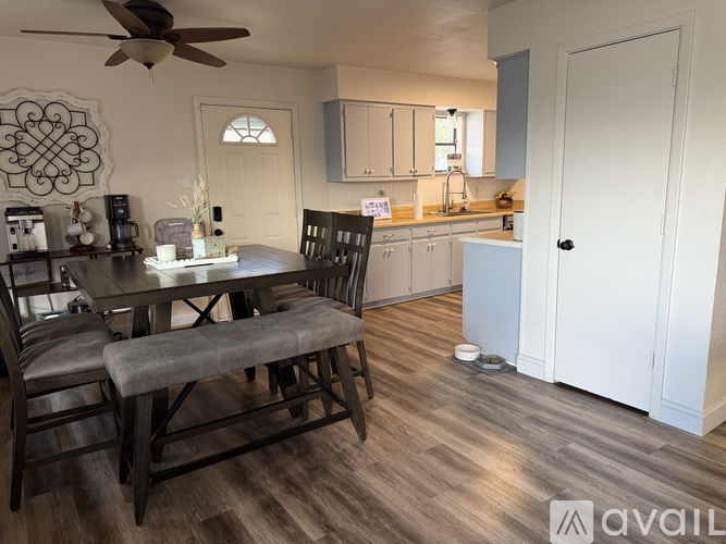 A dining room with a table set for two and a kitchen in the background.