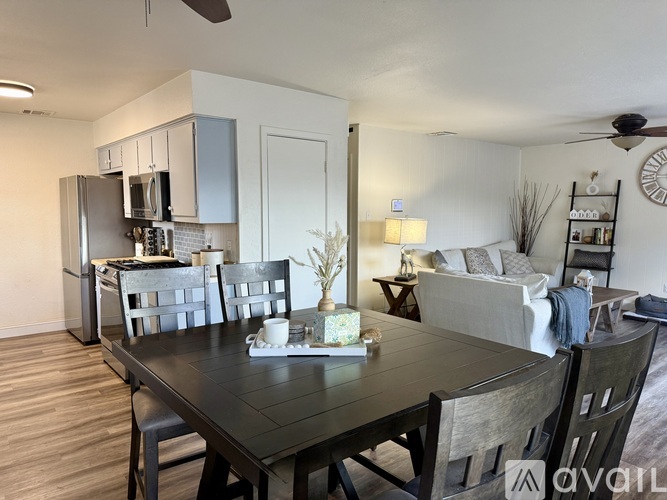 A dining room with a table set for two and chairs around it.