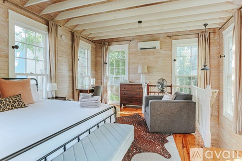 A bedroom with a large bed and a grey ottoman.
