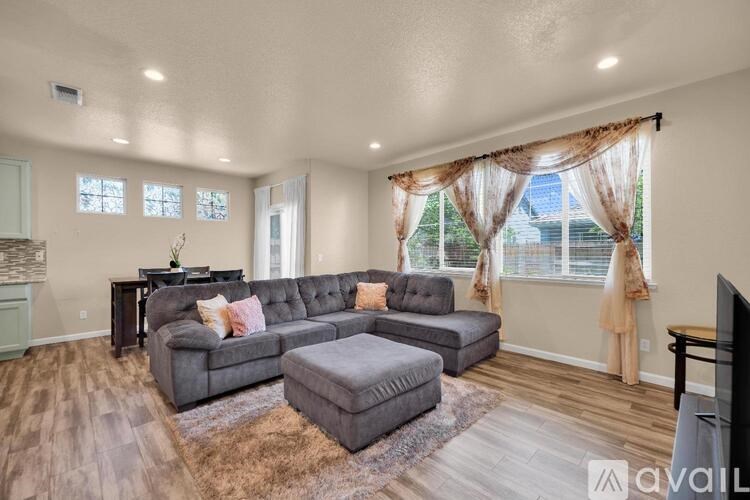 A living room with a grey sofa and a brown rug.