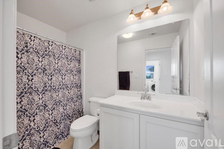 A bathroom with a floral shower curtain and a white sink.