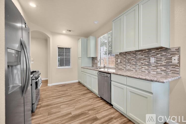 A kitchen with a refrigerator on the left and cabinets on the right.