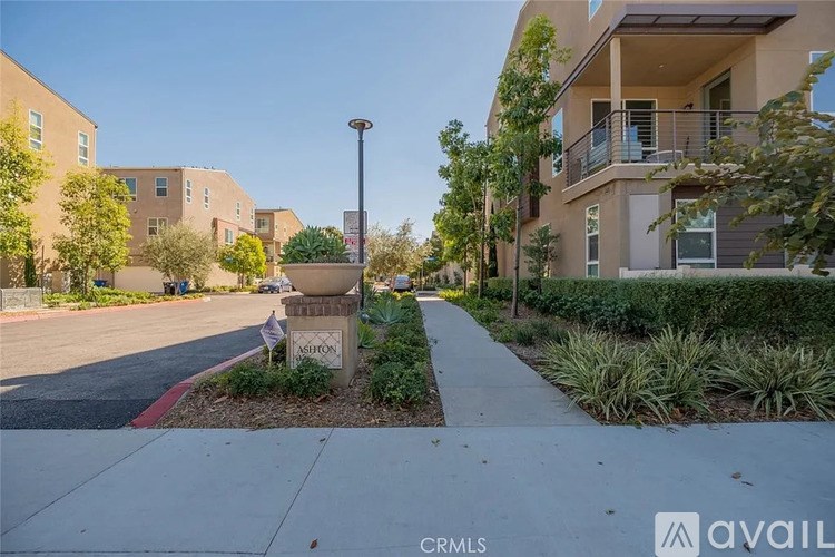 A street view of a residential area with apartment buildings and a sign that reads "CRMLS.".