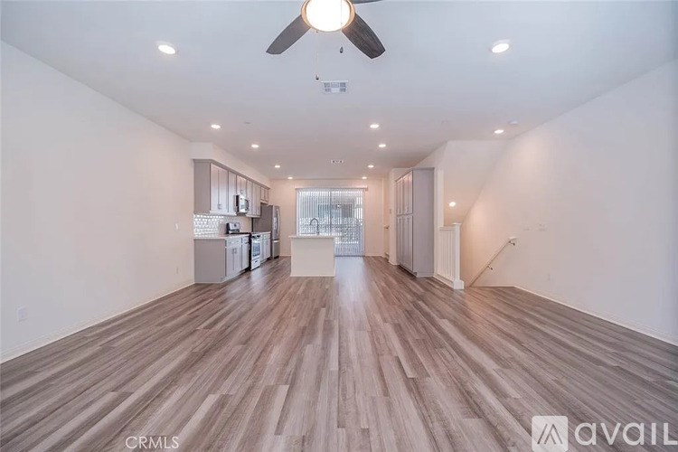 A spacious room with wooden flooring and a ceiling fan.