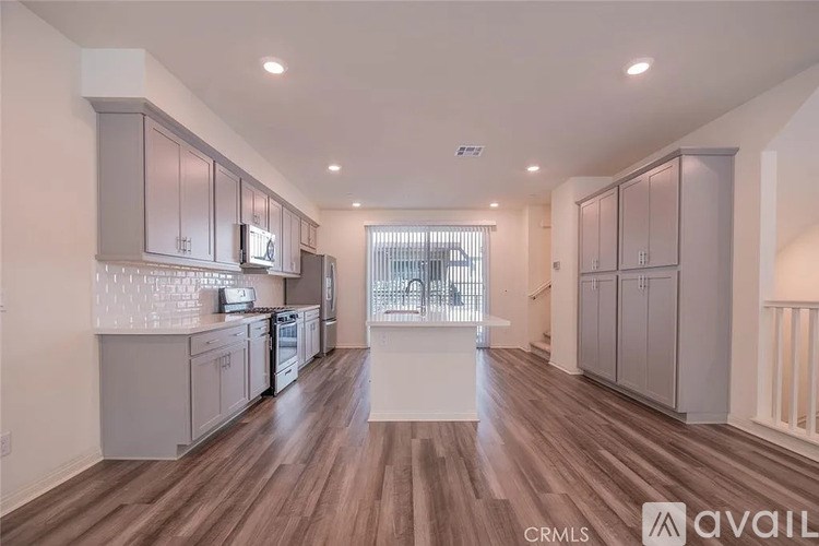 A spacious kitchen with wooden floors and grey cabinets.