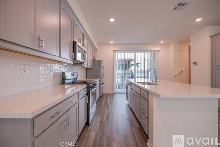 A kitchen with white countertops and wooden floors.