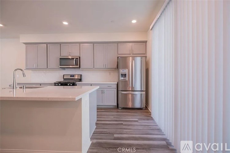 A kitchen with white cabinets and a stainless steel refrigerator.