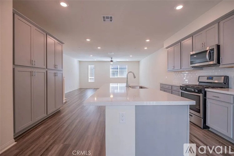 A kitchen with white cabinets and a white island with a microwave and oven.