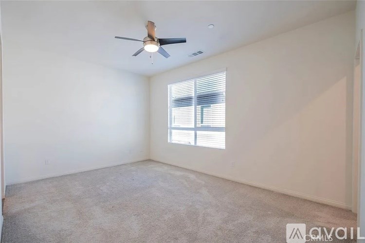 A room with a ceiling fan and a window with blinds.