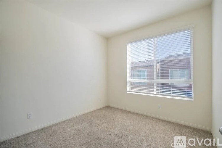 A room with a carpeted floor and a window with blinds.