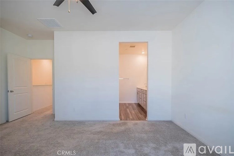 A room with a carpeted floor and a ceiling fan.