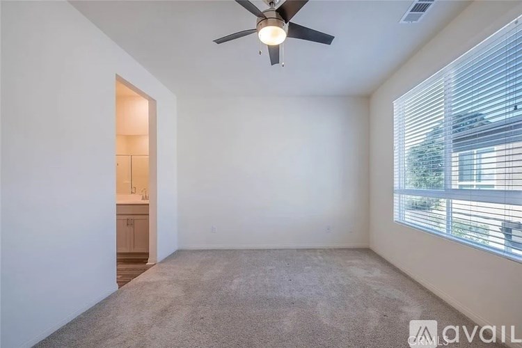 A room with a ceiling fan and carpeted floor.