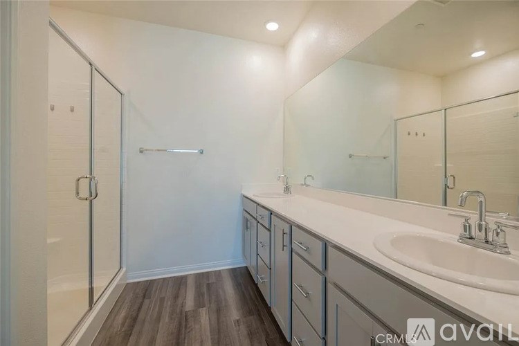 A bathroom with a sink, mirror, and shower.