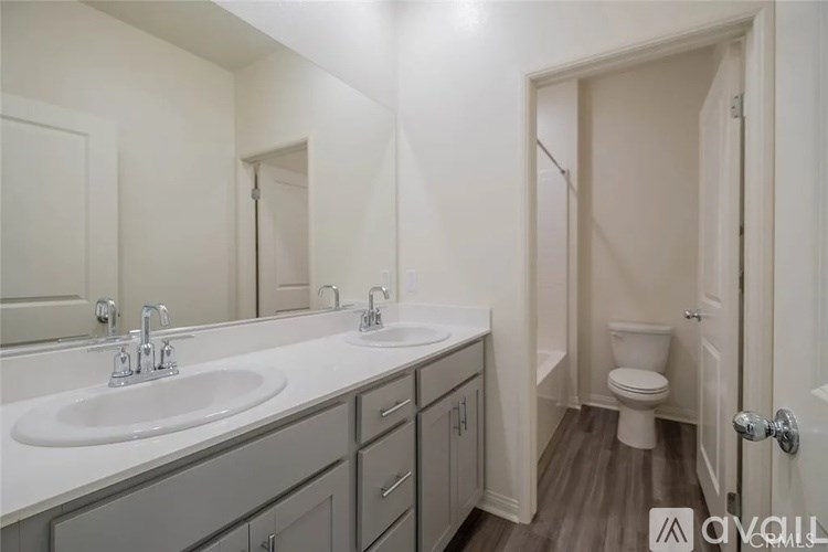 A bathroom with a sink, mirror, toilet and a door.