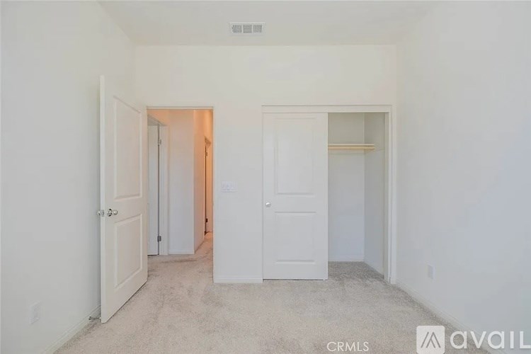 A white bedroom with a door on the left and a door on the right.