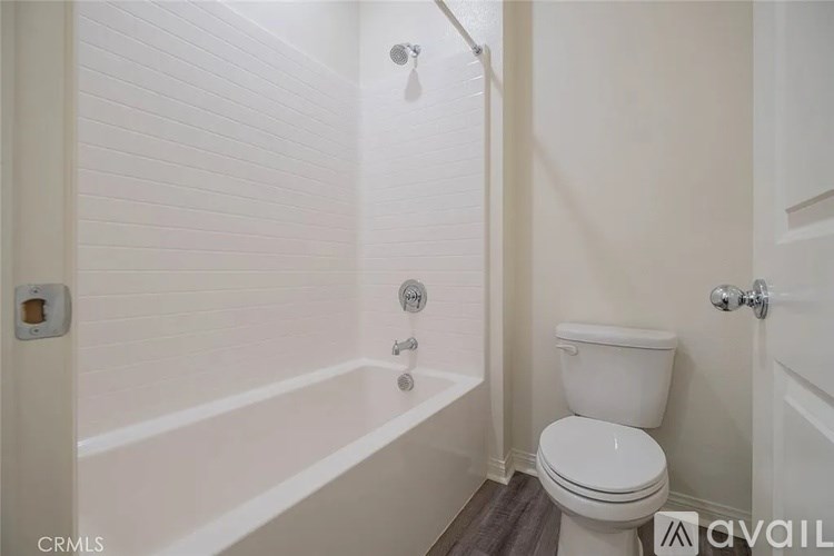 A white toilet in a bathroom with a white shower.