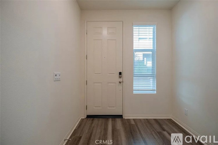 A white door is in a room with wooden floors and white walls.