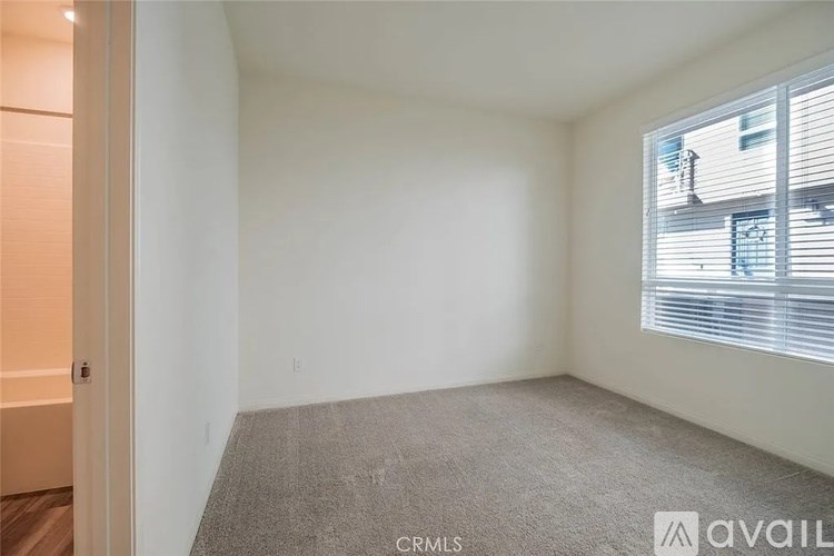 A room with a carpeted floor and a window with blinds.