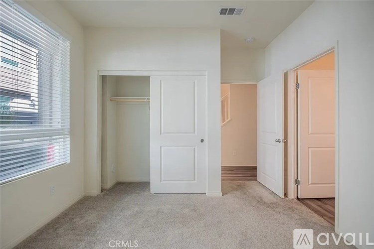 A bedroom with a white door and a window with blinds.