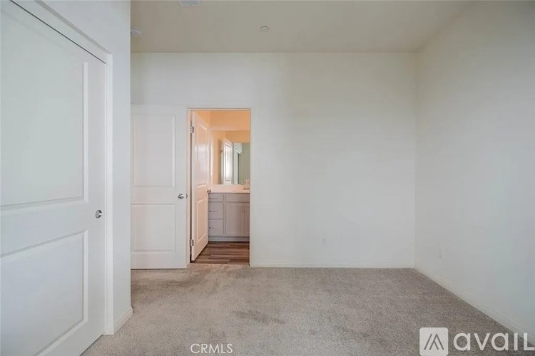 A room with a carpeted floor and a doorway leading to another room.