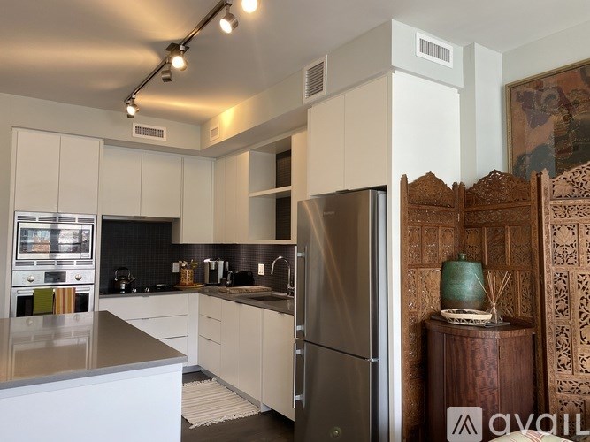 A modern kitchen with white cabinets and a stainless steel refrigerator.