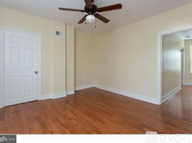 A room with a ceiling fan and wooden floors.