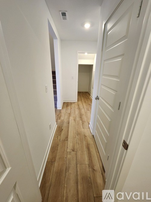 A long hallway with wood floors and white walls.