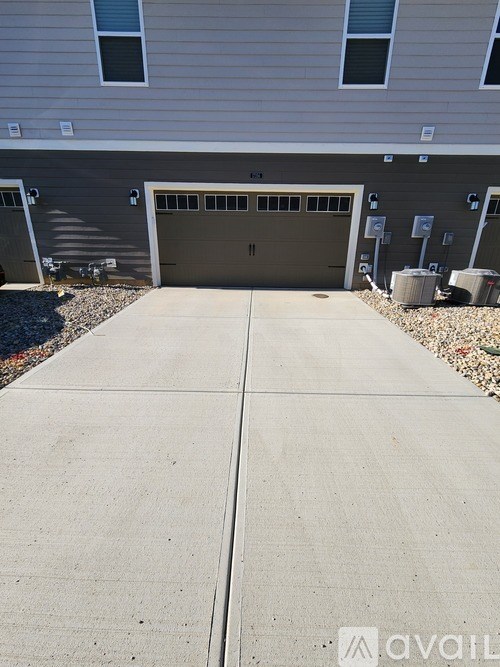A concrete driveway leads to a garage door of a house.