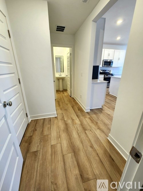 A hallway with wood flooring and white walls.