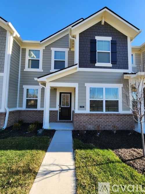 A two-story house with a front porch and a tree in front.