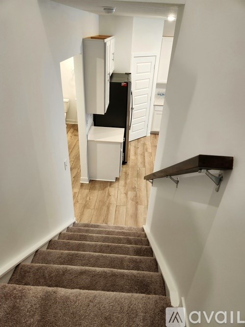 A staircase with a carpeted runner and a black handrail.