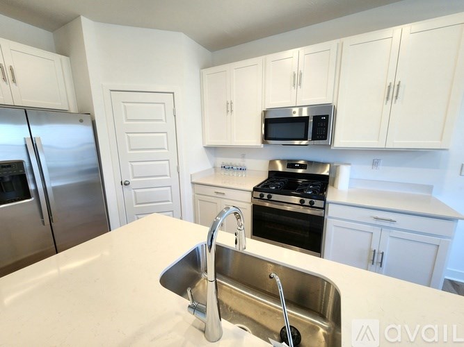 A kitchen with white cabinets and a stainless steel refrigerator.