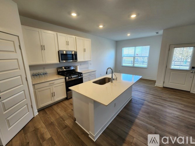 A kitchen with white cabinets and a wooden floor.