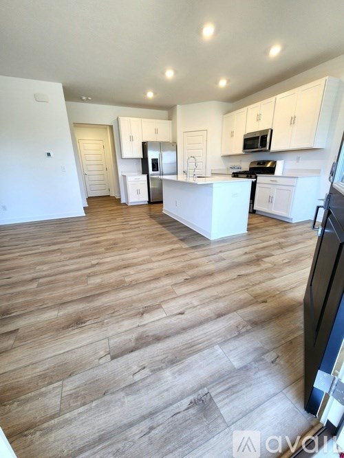 A kitchen with white cabinets and a wooden floor.
