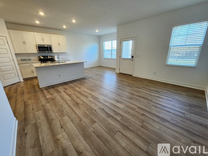 A spacious room with wooden flooring and white walls.