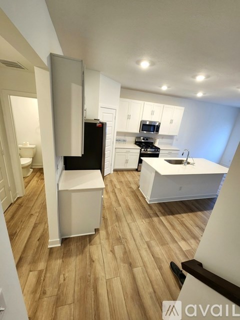 A kitchen with white cabinets and a wooden floor.