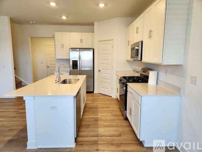 A kitchen with white cabinets and a wooden floor.