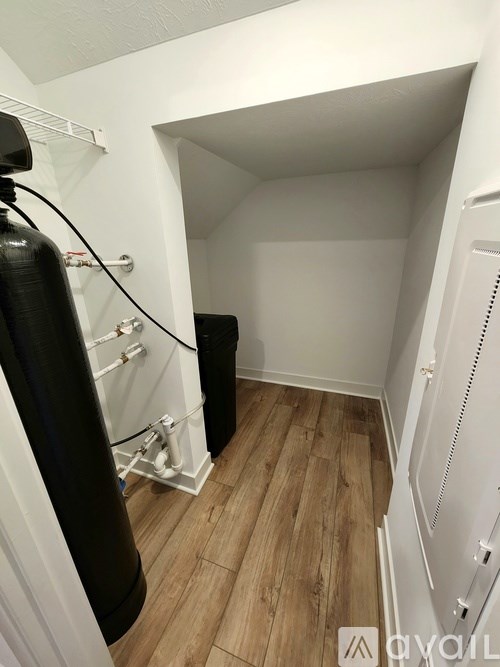 A white closet with a black vacuum cleaner.