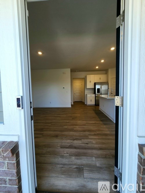 A hallway with wooden floors and a brick wall on the left.