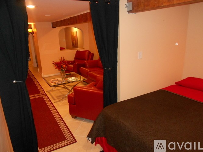 A bedroom with a red couch and a brown bed.
