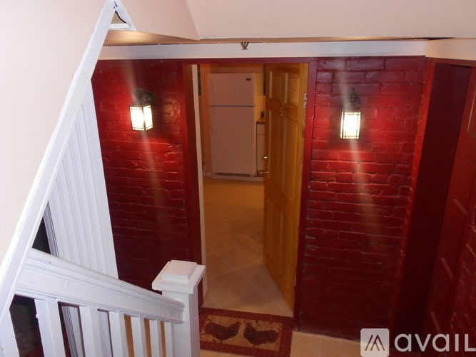 A hallway with a red brick wall and a white railing.