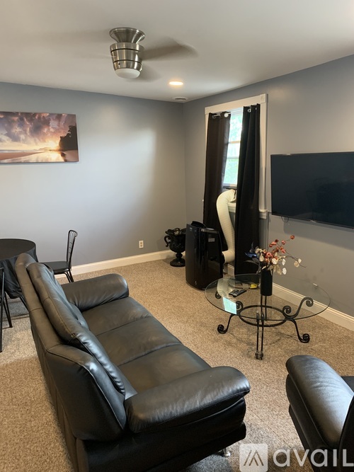 A living room with black leather furniture and a painting on the wall.