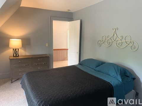 A bedroom with a bed, dresser, and lamp.