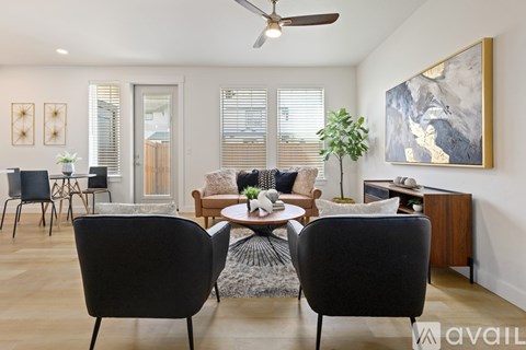 A living room with a black chair in the foreground and a painting on the wall.