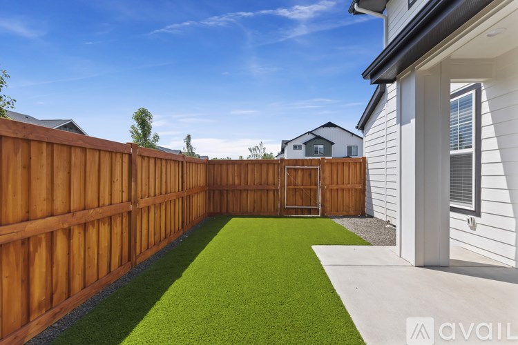 A backyard with a wooden fence and a green lawn.