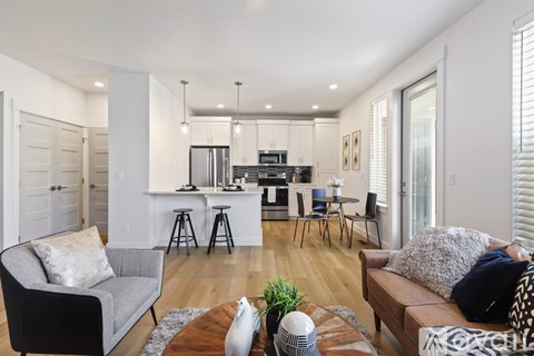 A modern living room with a kitchen in the background.