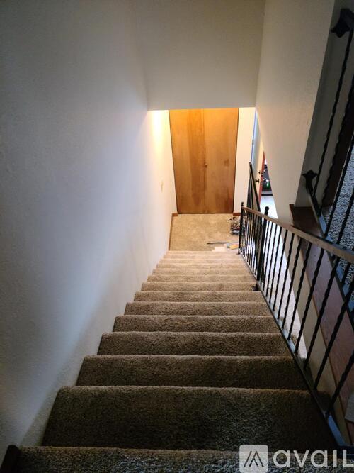 A staircase with a carpeted runner and a metal railing.