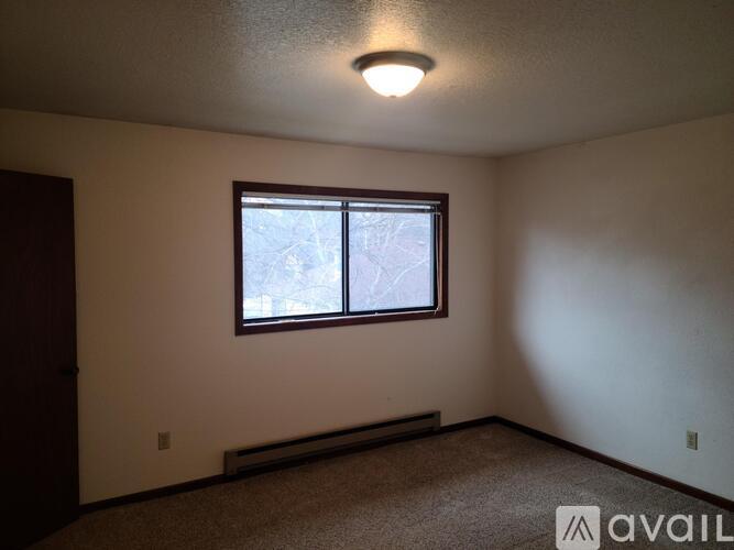 A room with a window and a carpeted floor.